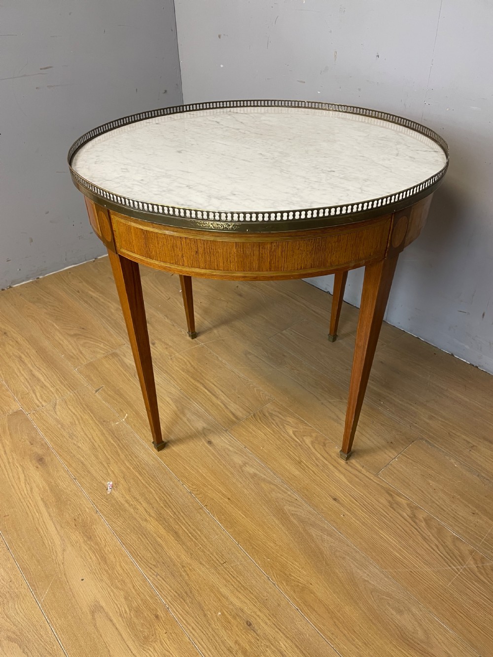 A late 19th-century French circular Bouillotte table featuring a white marble top with a pierced brass gallery, a veneered apron with a small drawer, and four square tapered legs ending in brass sabots. View XI