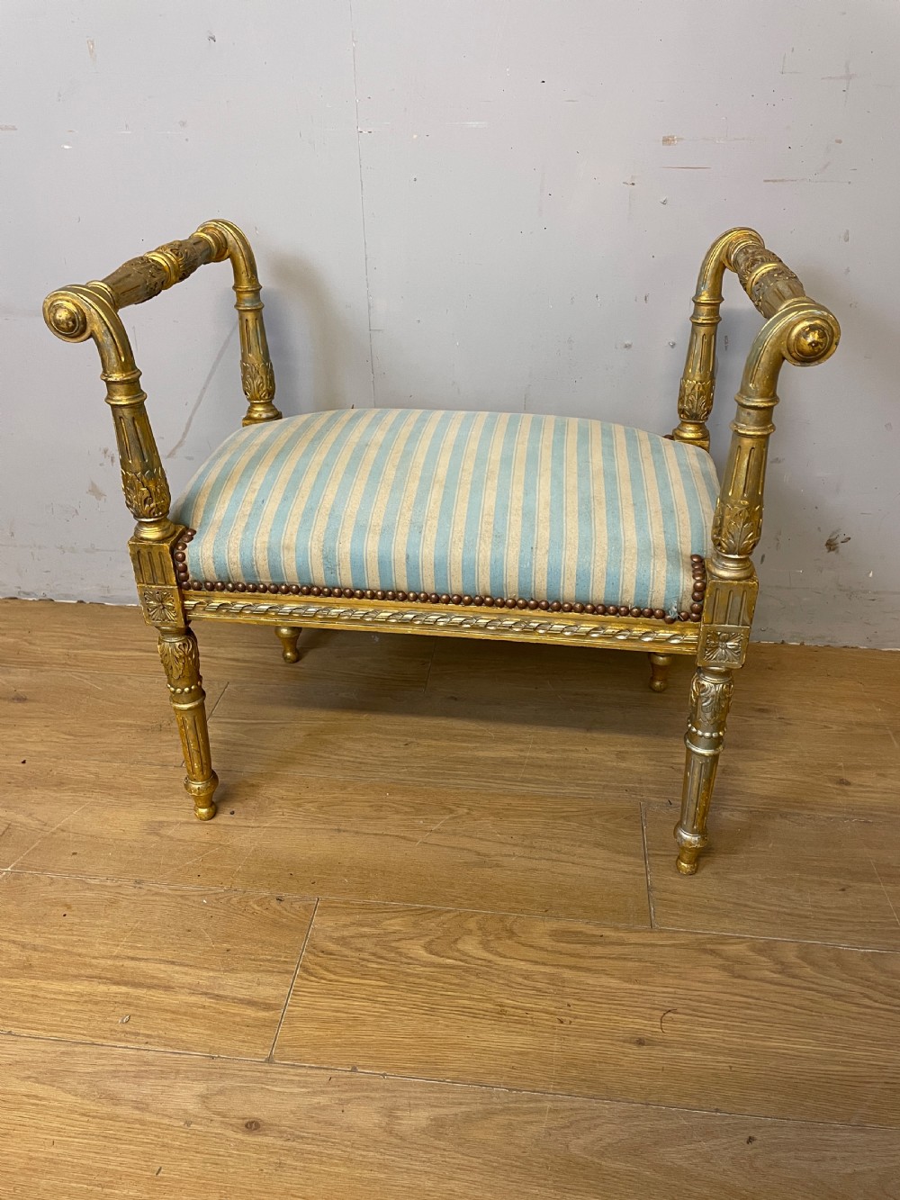 A Louis XVI style French giltwood window seat featuring rolled arms, fluted tapering legs, and blue and cream striped upholstery. View III