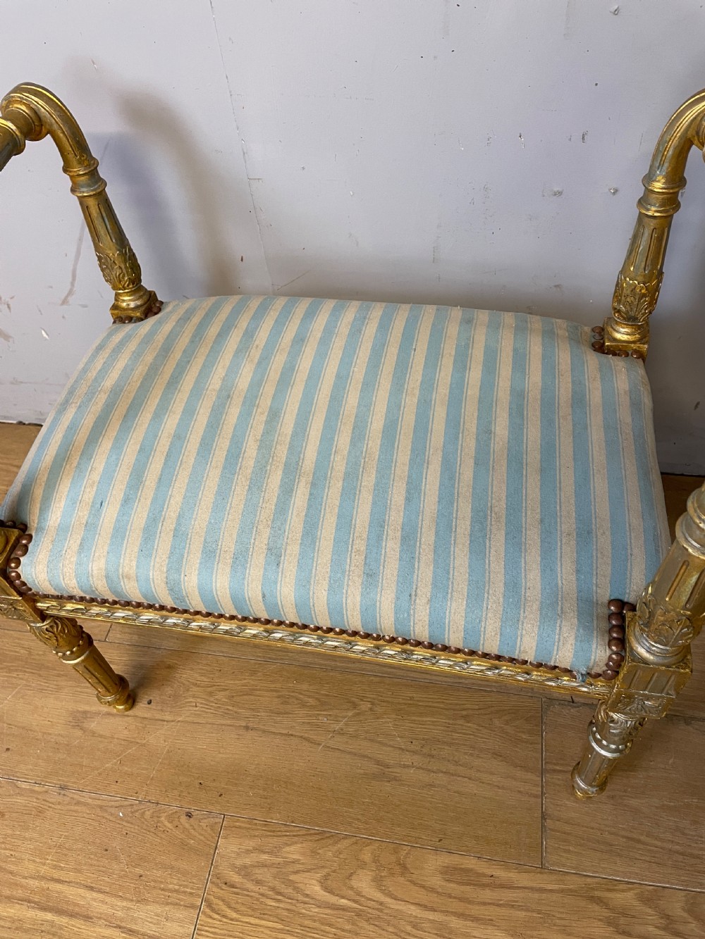 A Louis XVI style French giltwood window seat featuring rolled arms, fluted tapering legs, and blue and cream striped upholstery. View VII