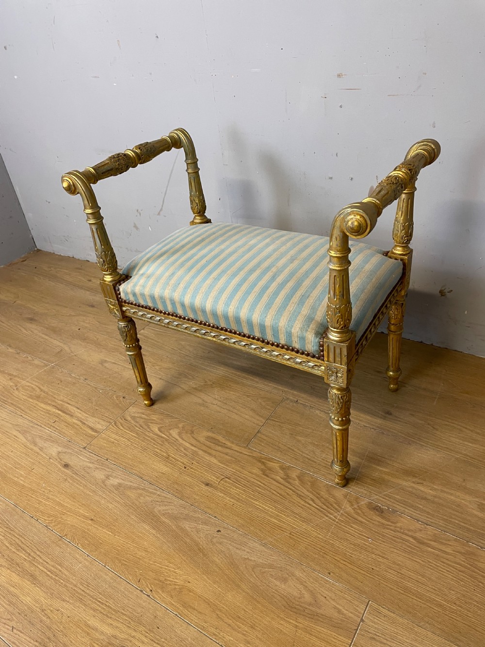 A Louis XVI style French giltwood window seat featuring rolled arms, fluted tapering legs, and blue and cream striped upholstery. View X