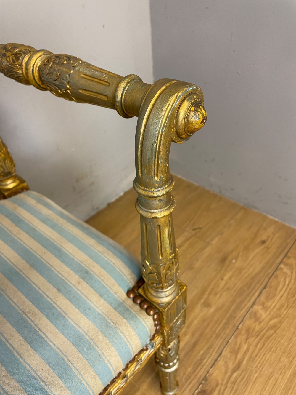 A Louis XVI style French giltwood window seat featuring rolled arms, fluted tapering legs, and blue and cream striped upholstery. View XII