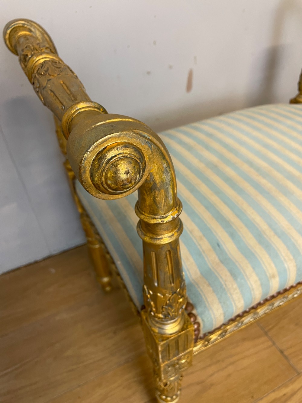 A Louis XVI style French giltwood window seat featuring rolled arms, fluted tapering legs, and blue and cream striped upholstery. View XIII