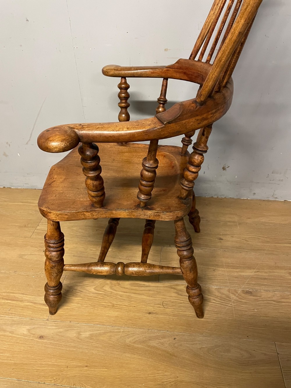 A 19th-century ash and elm Windsor armchair featuring a hoop back, pierced central splat, turned arm supports, and a solid contoured seat. View X