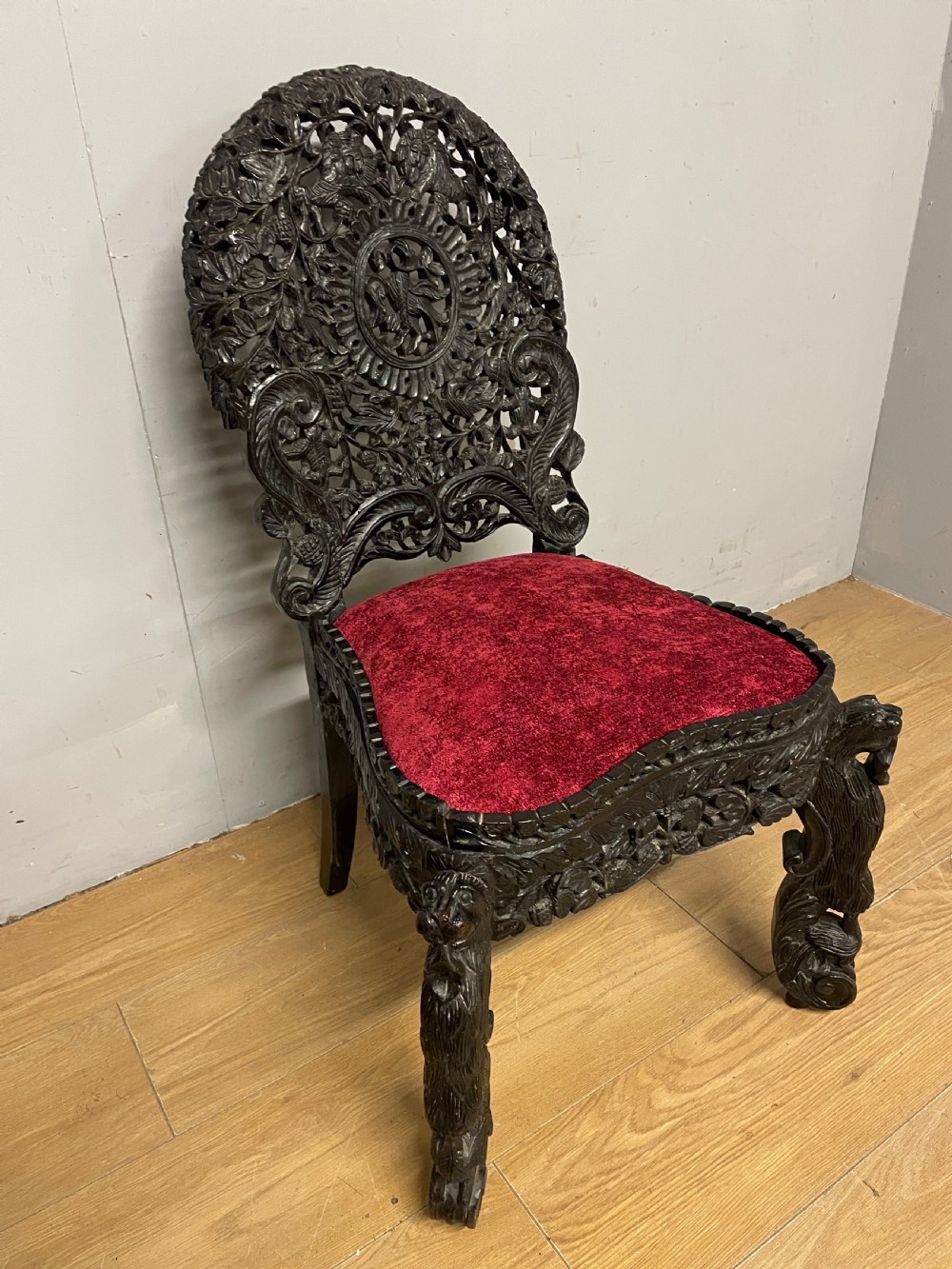 A 19th-century Burmese side chair featuring an intricately carved dark wood openwork backrest and animal-shaped cabriole legs with a red velvet upholstered seat. View III