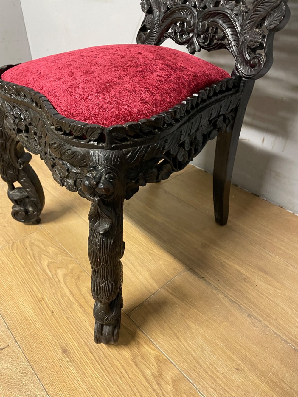 A 19th-century Burmese side chair featuring an intricately carved dark wood openwork backrest and animal-shaped cabriole legs with a red velvet upholstered seat. View VII