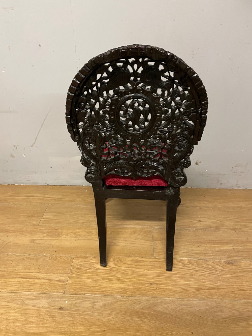 A 19th-century Burmese side chair featuring an intricately carved dark wood openwork backrest and animal-shaped cabriole legs with a red velvet upholstered seat. View X