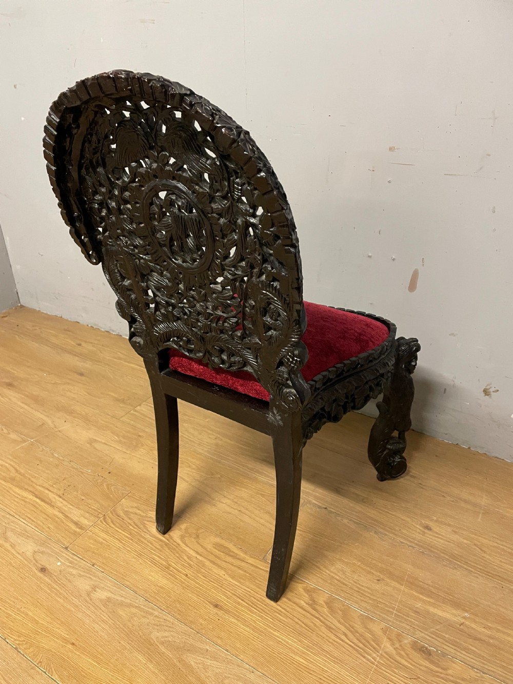 A 19th-century Burmese side chair featuring an intricately carved dark wood openwork backrest and animal-shaped cabriole legs with a red velvet upholstered seat. View XI