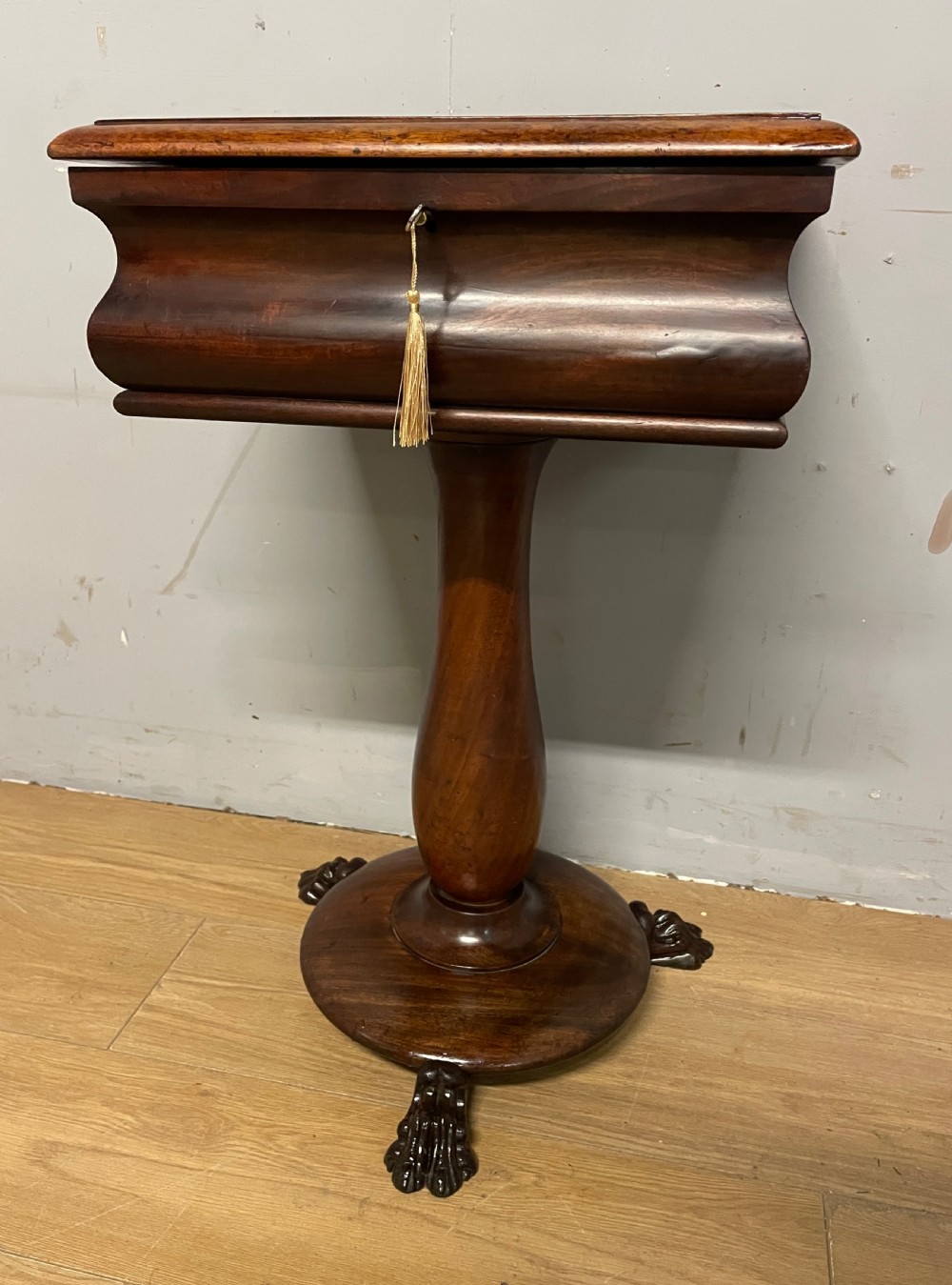 A Regency flame mahogany work table featuring a curved apron, central turned pedestal, circular plinth, and carved lion paw feet. View II