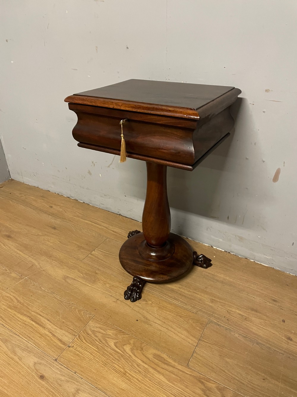 A Regency flame mahogany work table featuring a curved apron, central turned pedestal, circular plinth, and carved lion paw feet. View III