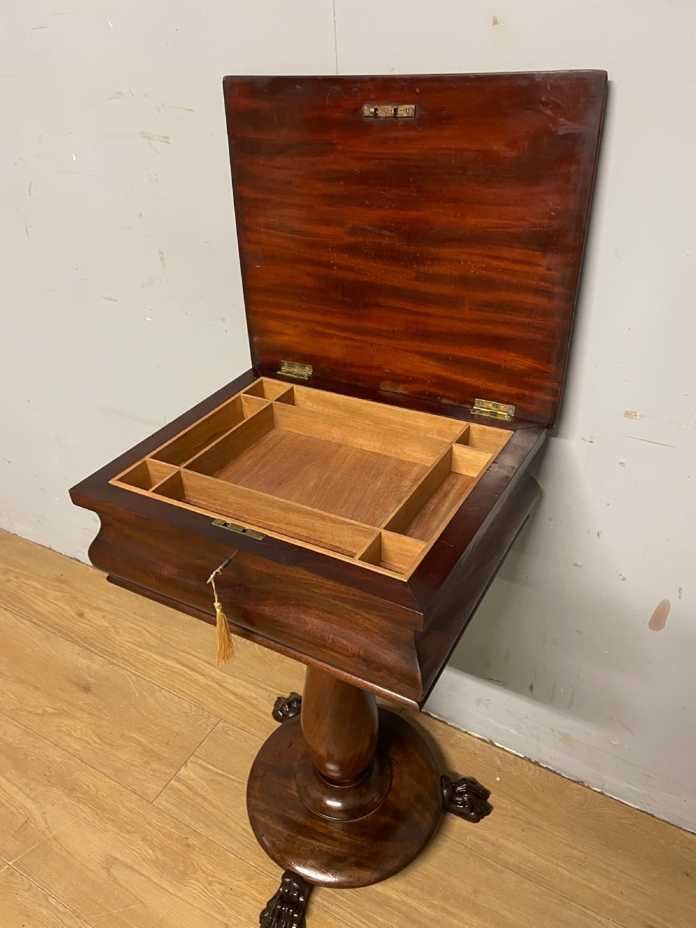 A Regency flame mahogany work table featuring a curved apron, central turned pedestal, circular plinth, and carved lion paw feet. View VI