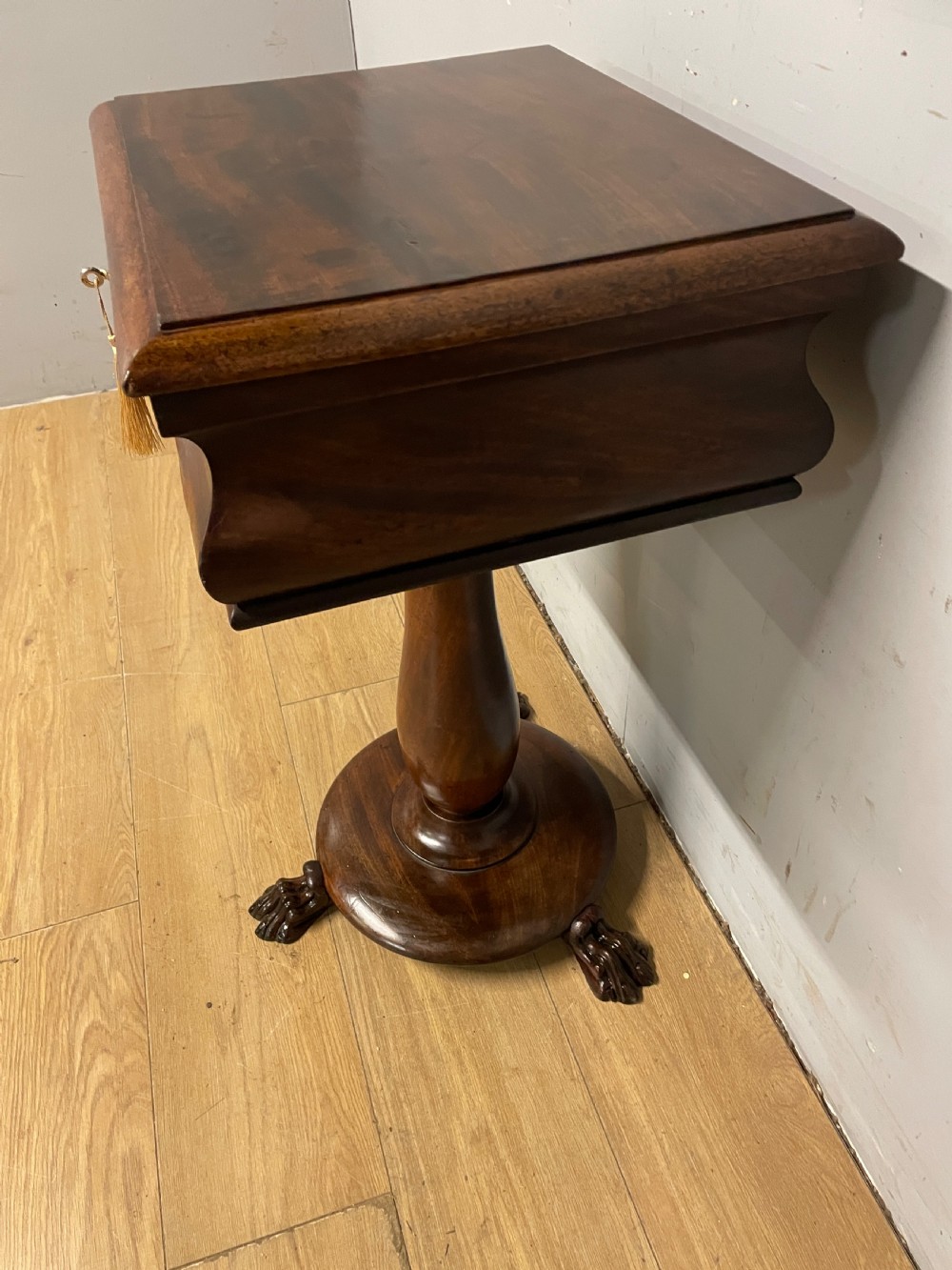 A Regency flame mahogany work table featuring a curved apron, central turned pedestal, circular plinth, and carved lion paw feet. View IX