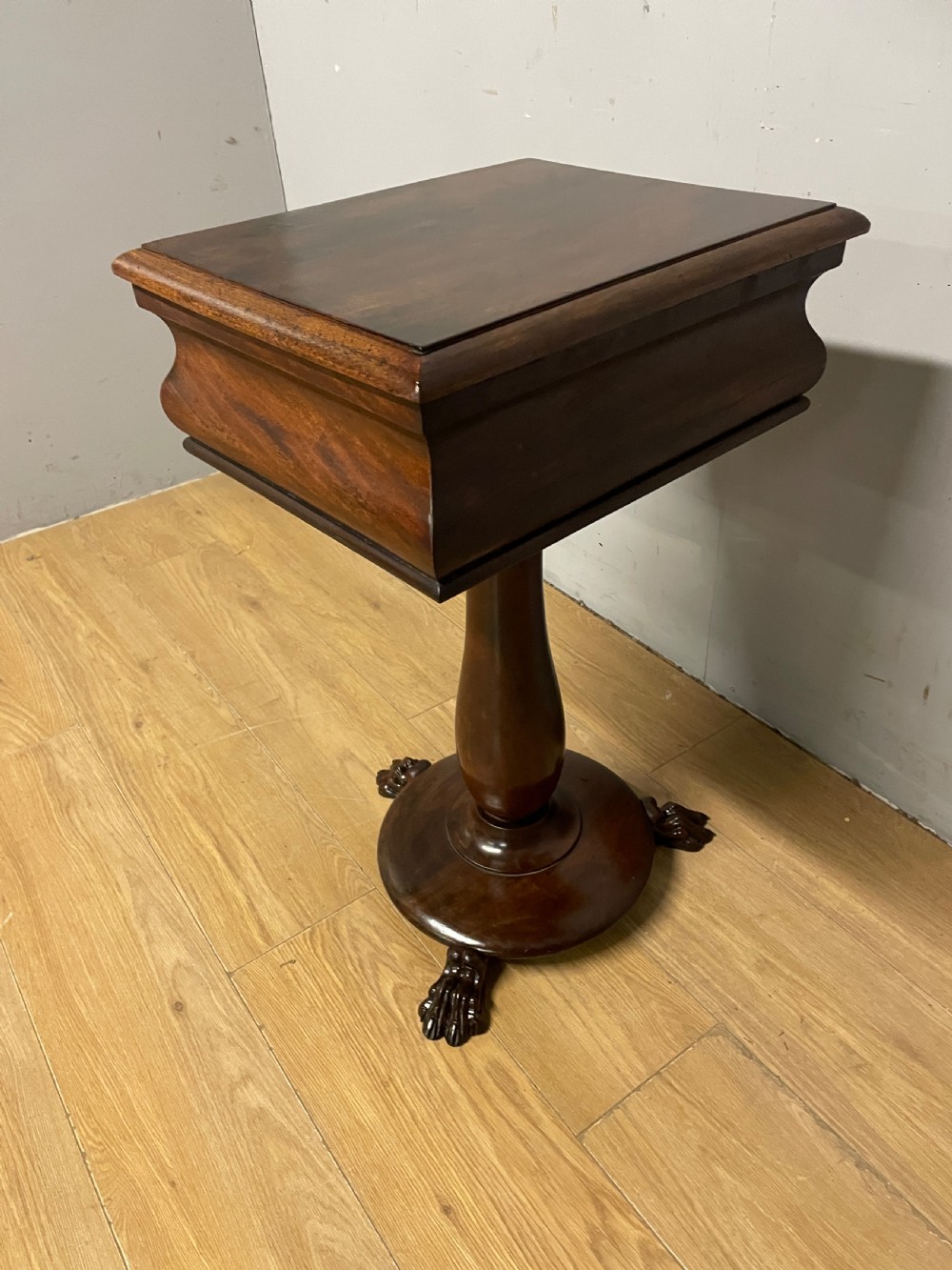 A Regency flame mahogany work table featuring a curved apron, central turned pedestal, circular plinth, and carved lion paw feet. View XI
