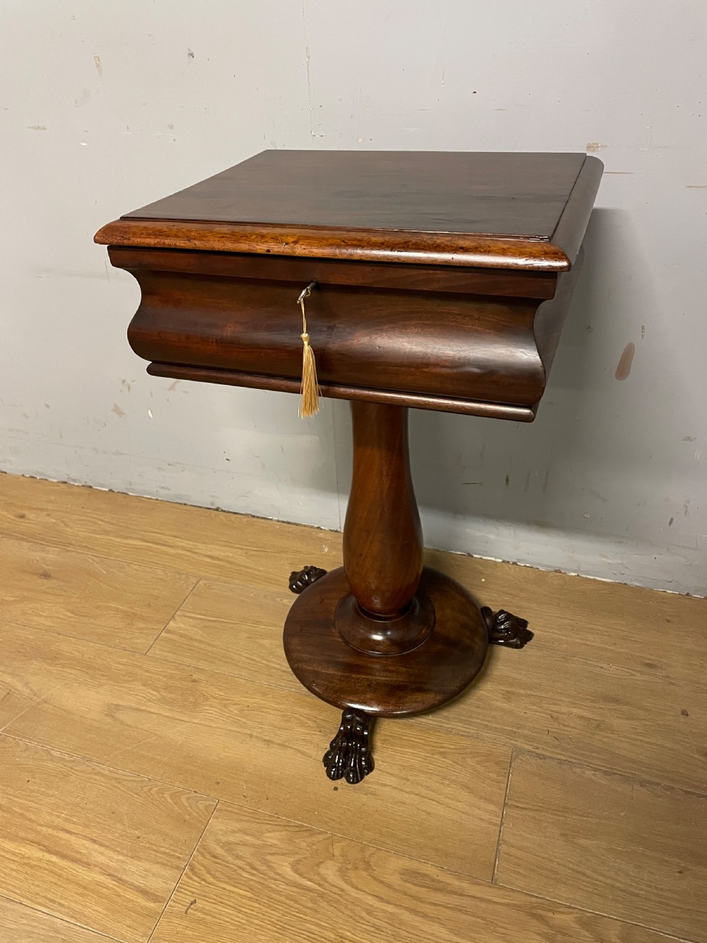 A Regency flame mahogany work table featuring a curved apron, central turned pedestal, circular plinth, and carved lion paw feet. View XIII