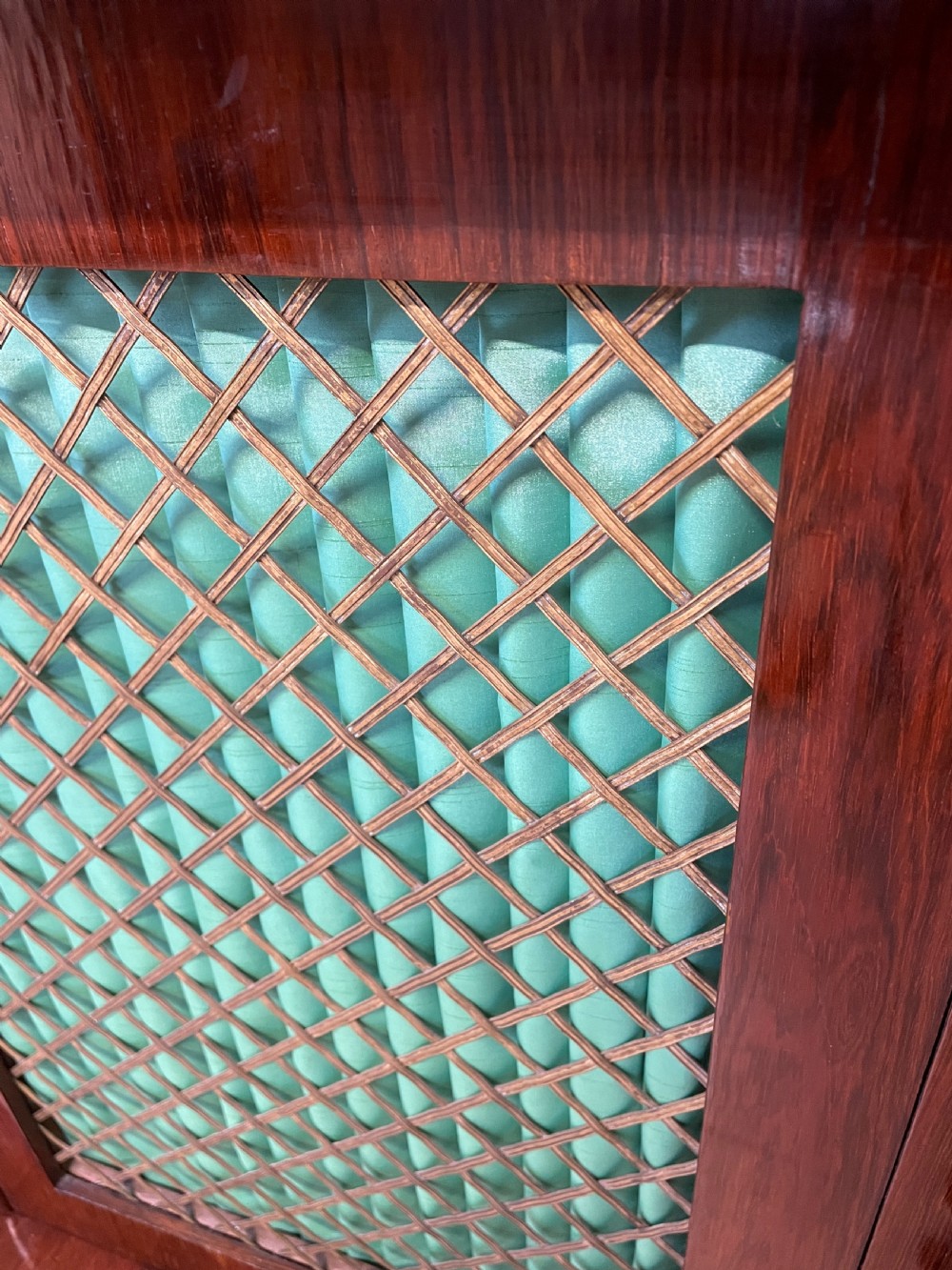 A late Regency rosewood chiffonier featuring barley twist columns, brass wire lattice doors backed with green pleated fabric, and a brass gallery top rail. View VII