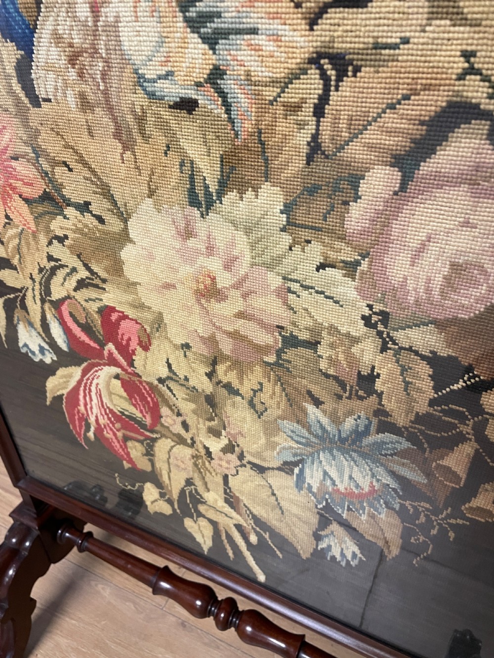 A nineteenth-century mahogany firescreen featuring a central needlepoint panel depicting a floral arrangement and bird, supported by carved splayed legs and a turned stretcher. View VII