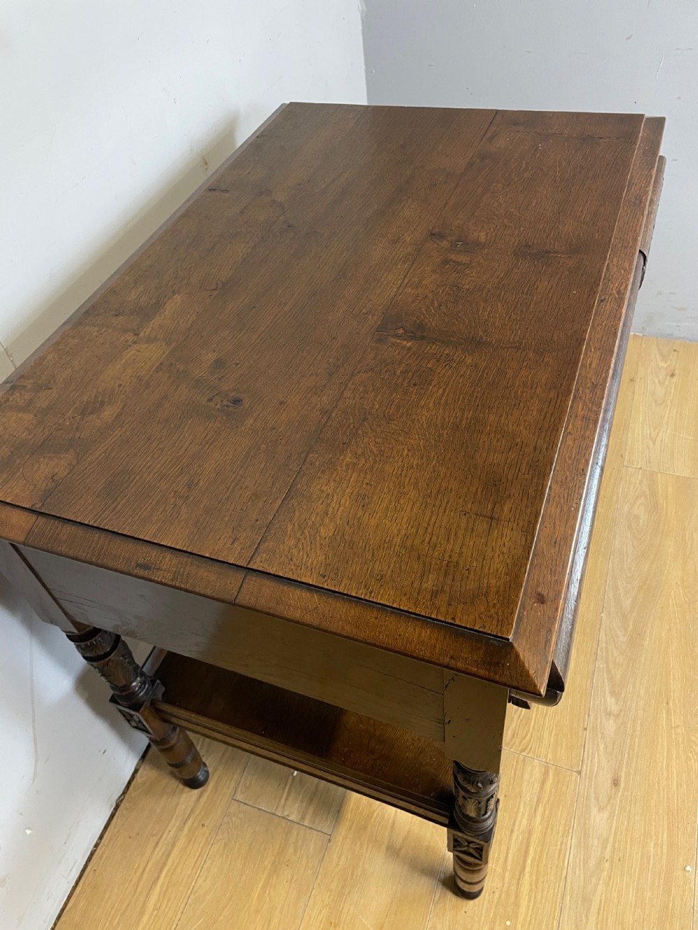 A 19th-century dark carved oak two-tier side table featuring turned legs and a detailed carved frieze. View III