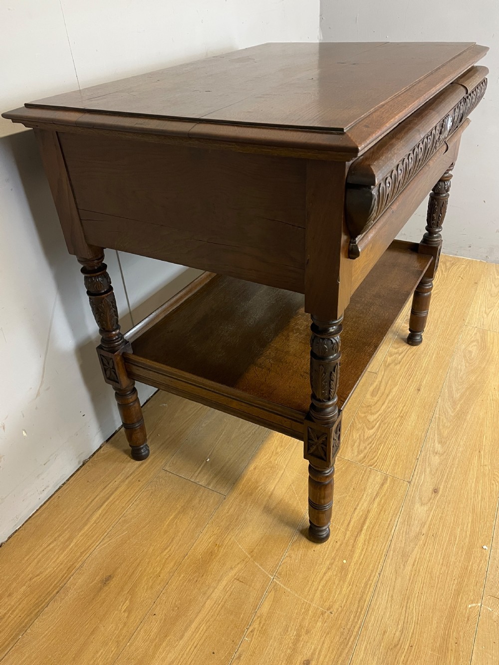 A 19th-century dark carved oak two-tier side table featuring turned legs and a detailed carved frieze. View IV