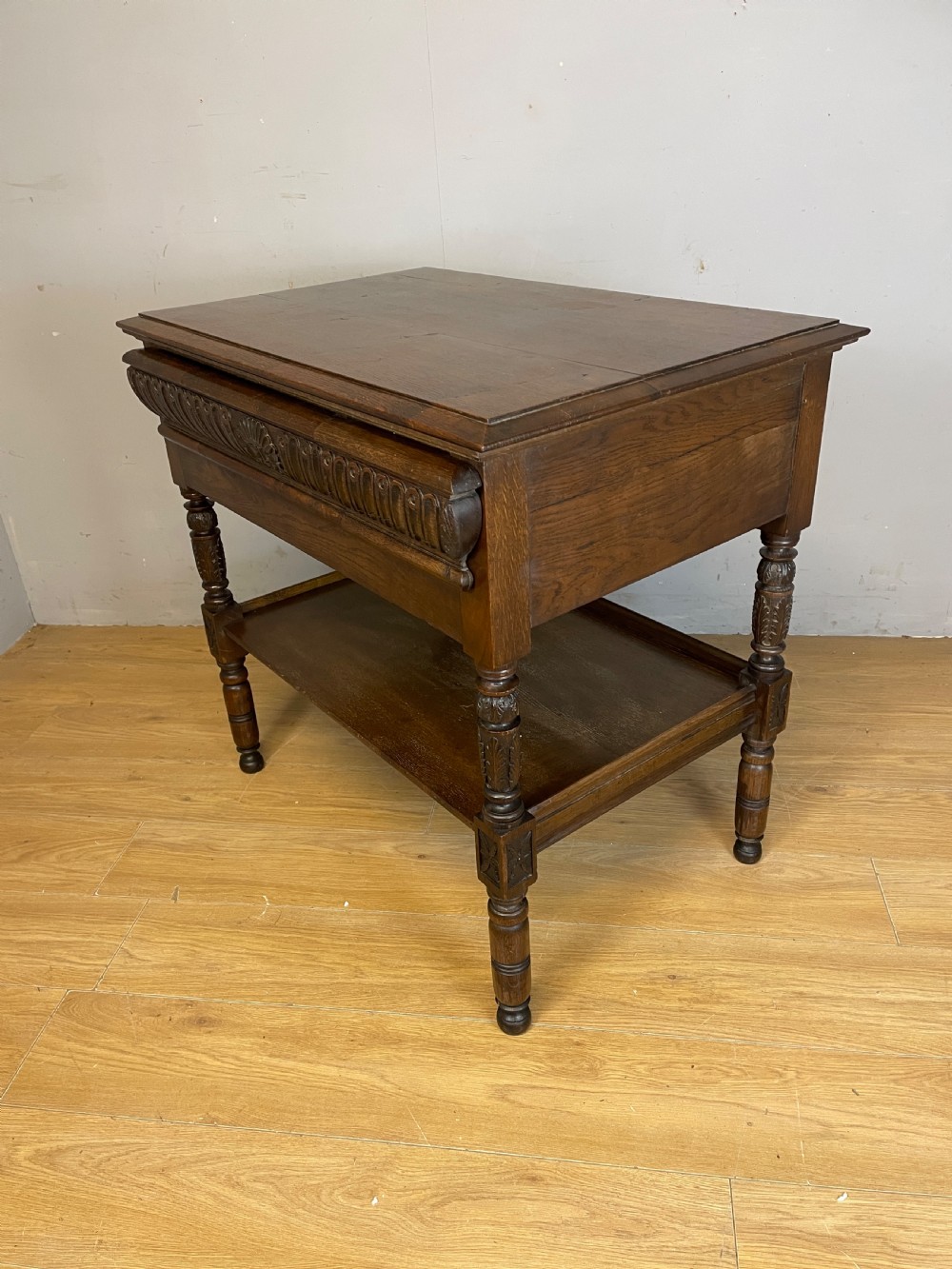 A 19th-century dark carved oak two-tier side table featuring turned legs and a detailed carved frieze. View VI
