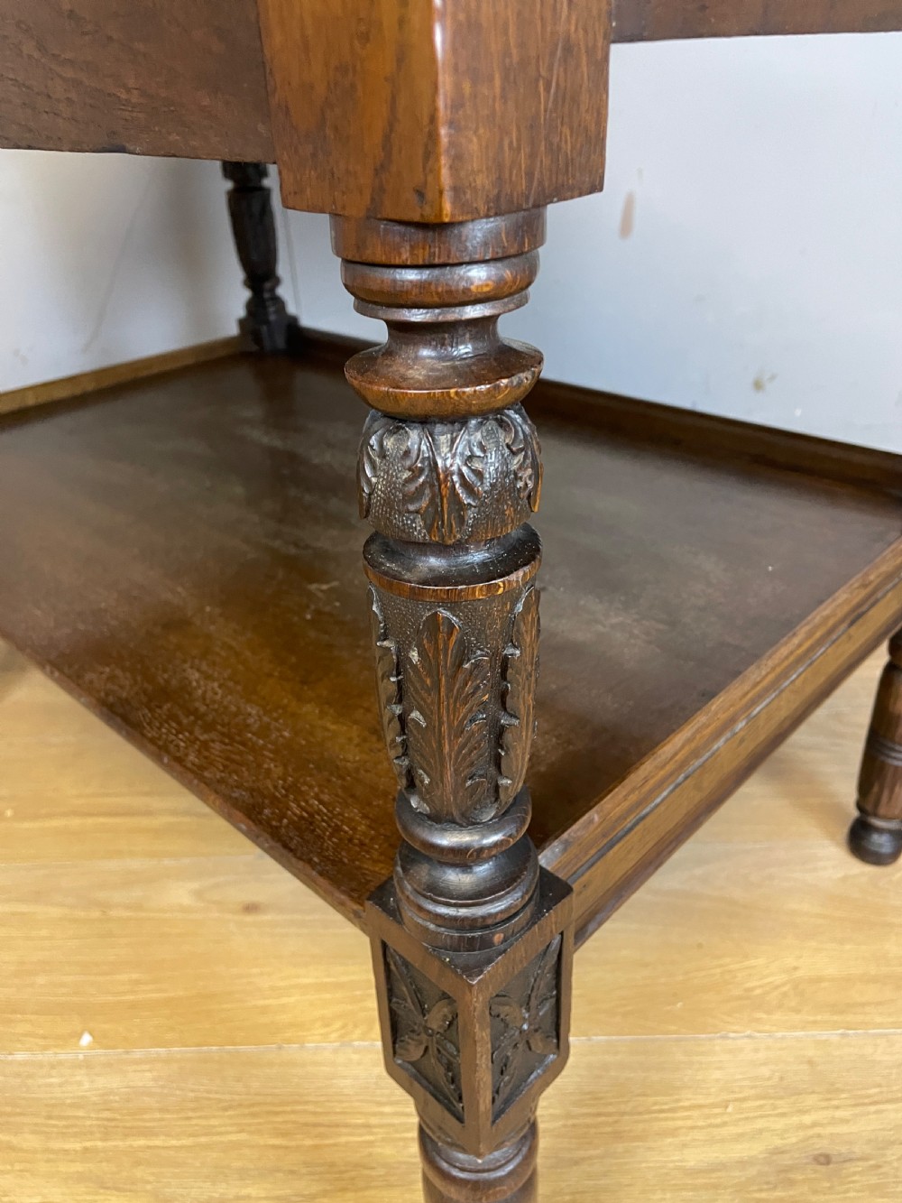 A 19th-century dark carved oak two-tier side table featuring turned legs and a detailed carved frieze. View VII
