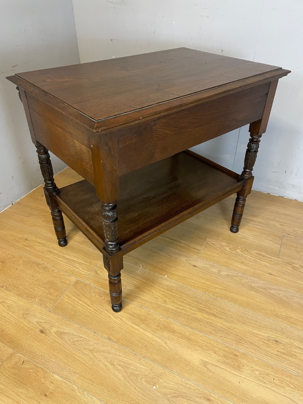 A 19th-century dark carved oak two-tier side table featuring turned legs and a detailed carved frieze. View IX