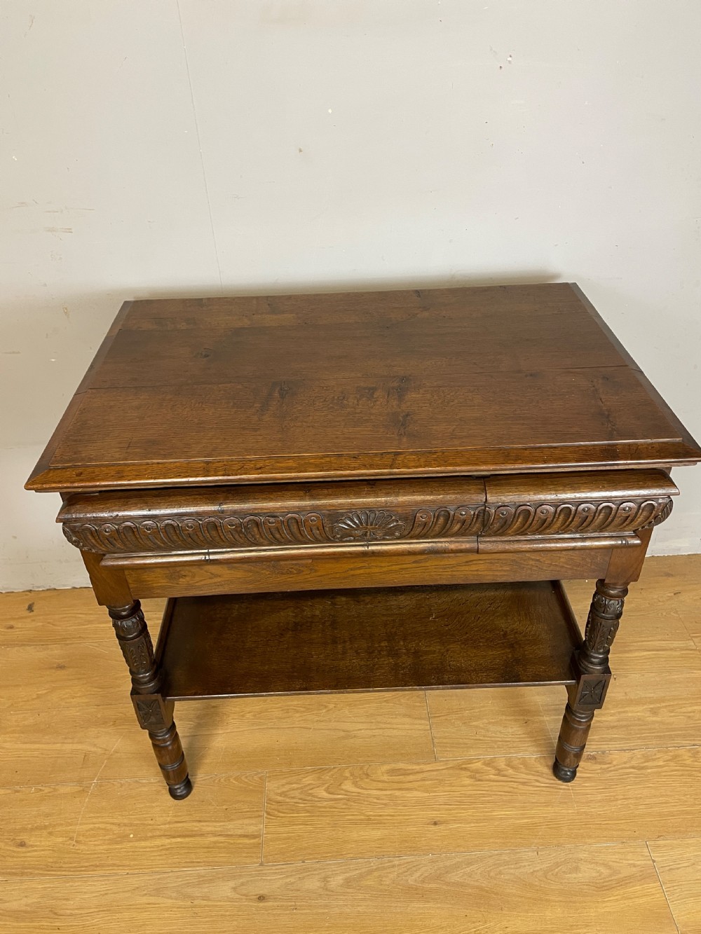 A 19th-century dark carved oak two-tier side table featuring turned legs and a detailed carved frieze. View XI