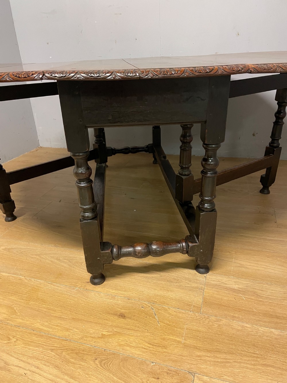 A large 19th-century dark oak drop-leaf dining table featuring turned gatelegs and a carved egg-and-dart motif along the oval table top border. View II