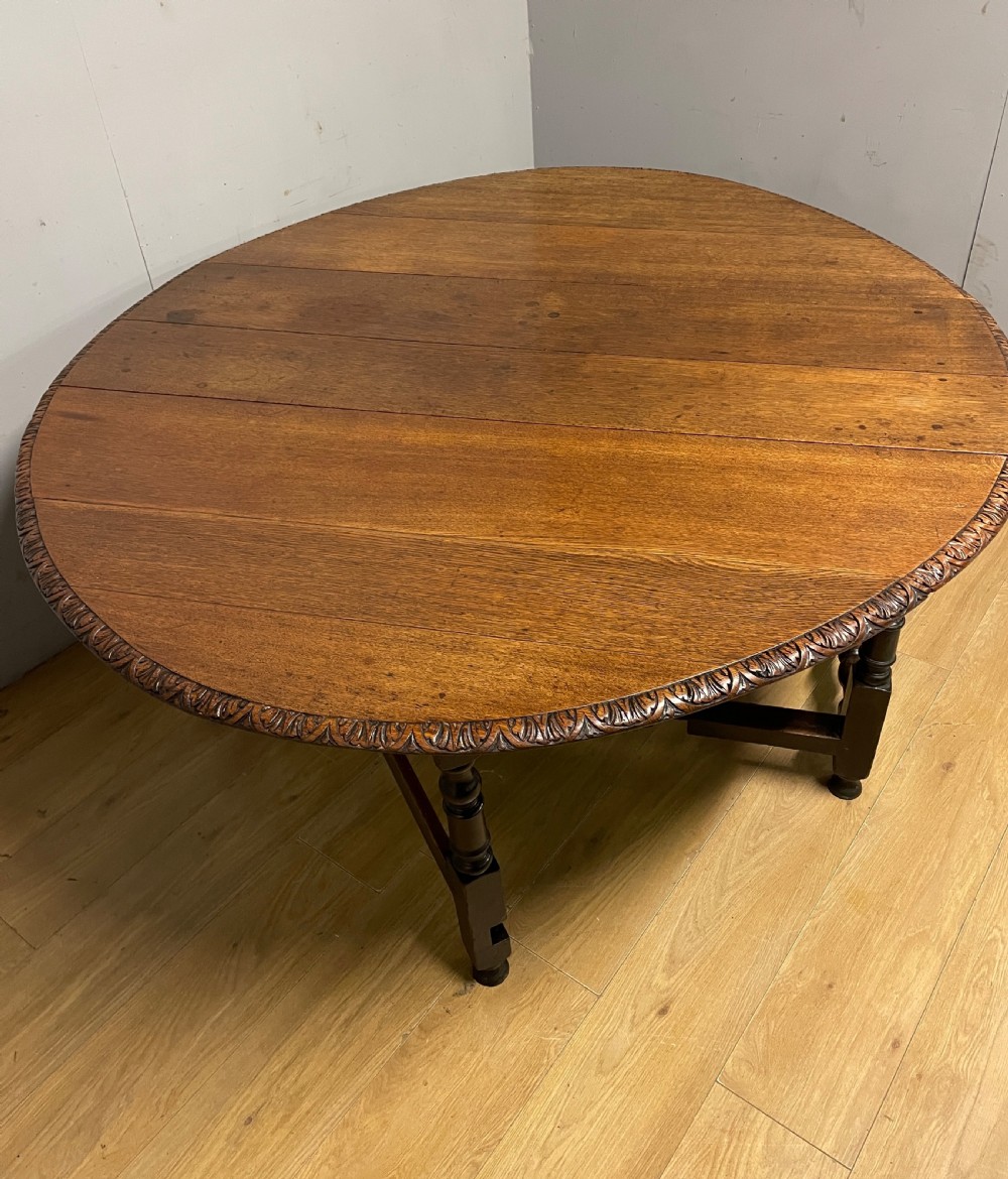 A large 19th-century dark oak drop-leaf dining table featuring turned gatelegs and a carved egg-and-dart motif along the oval table top border. View III