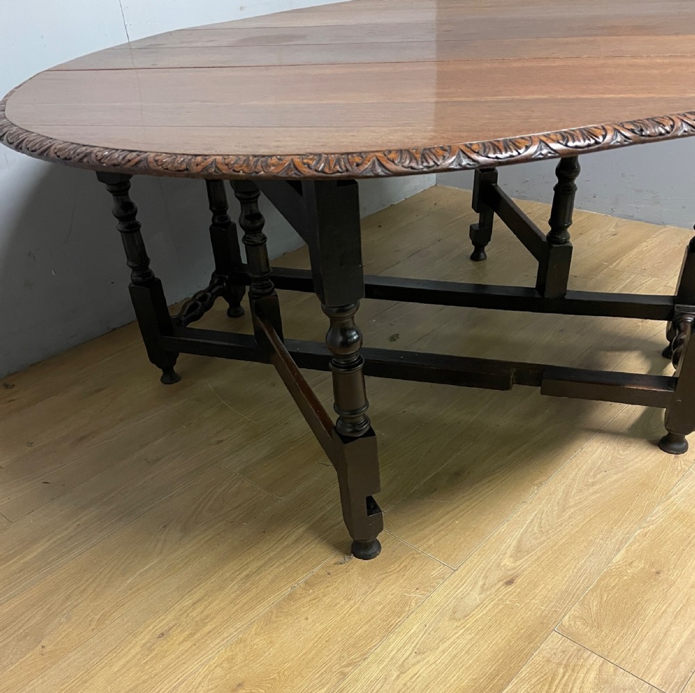 A large 19th-century dark oak drop-leaf dining table featuring turned gatelegs and a carved egg-and-dart motif along the oval table top border. View IV