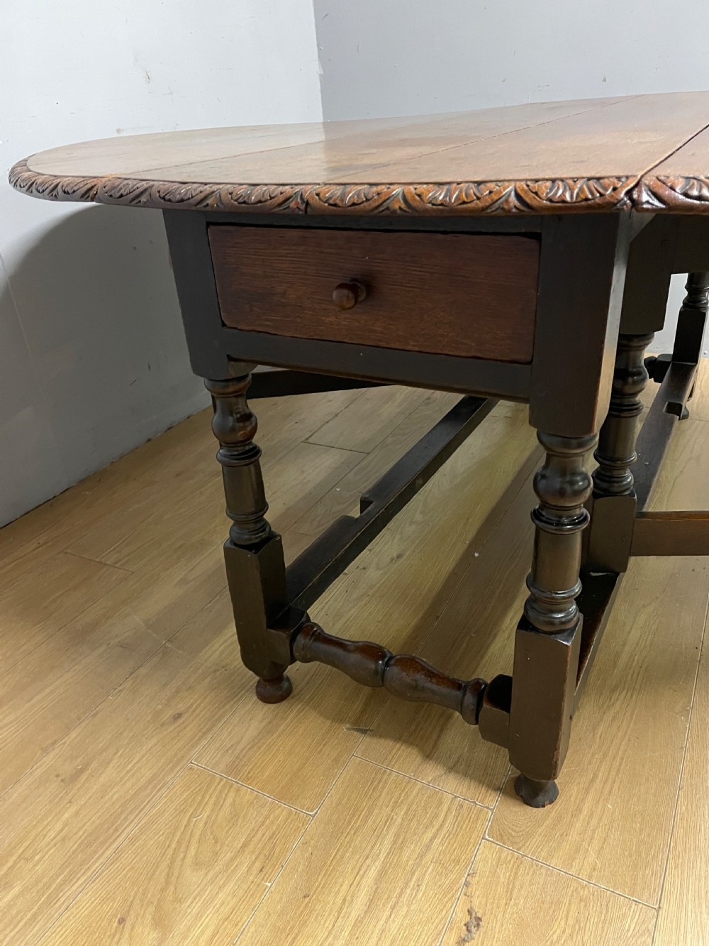 A large 19th-century dark oak drop-leaf dining table featuring turned gatelegs and a carved egg-and-dart motif along the oval table top border. View VI