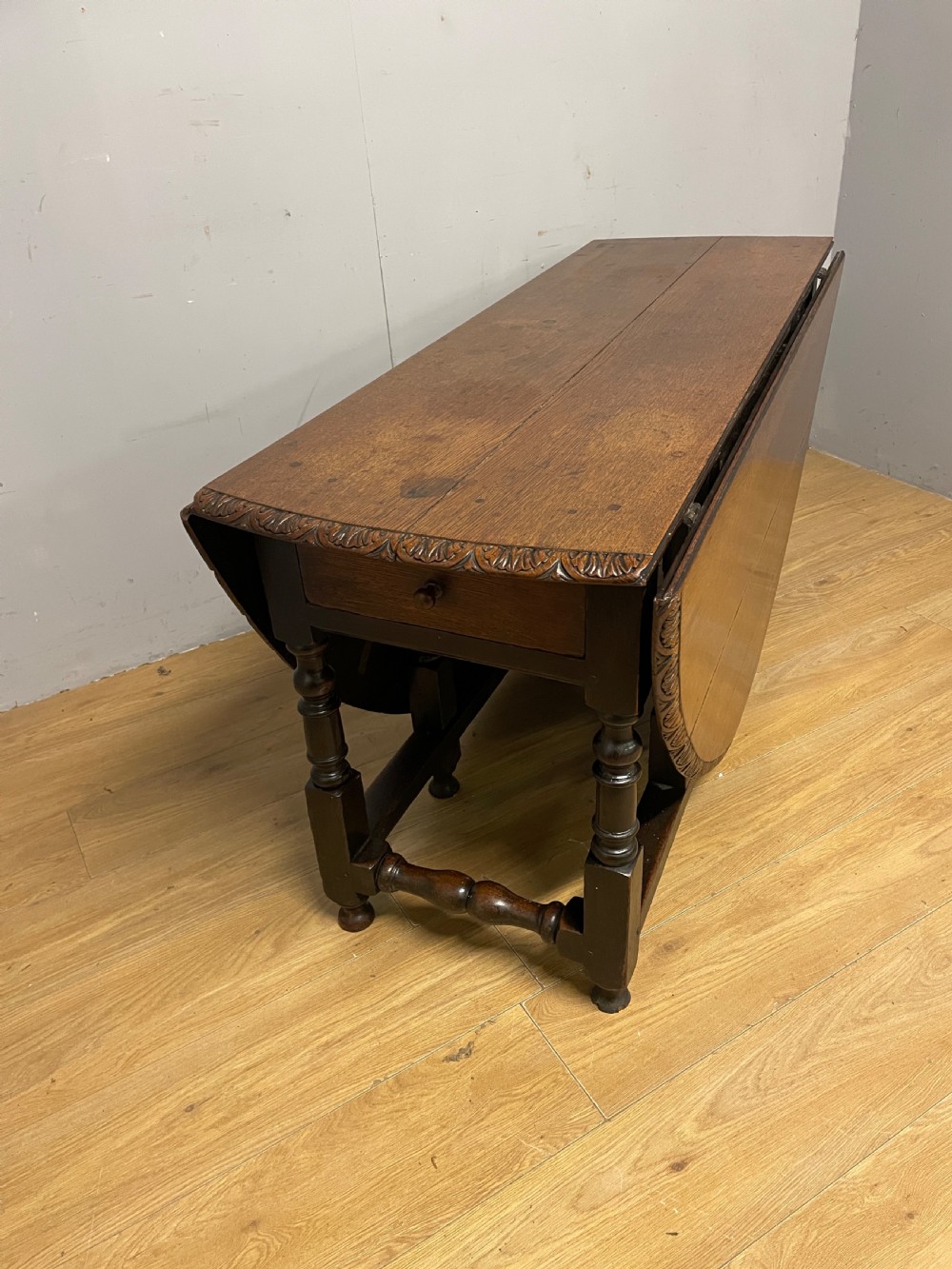 A large 19th-century dark oak drop-leaf dining table featuring turned gatelegs and a carved egg-and-dart motif along the oval table top border. View VIII