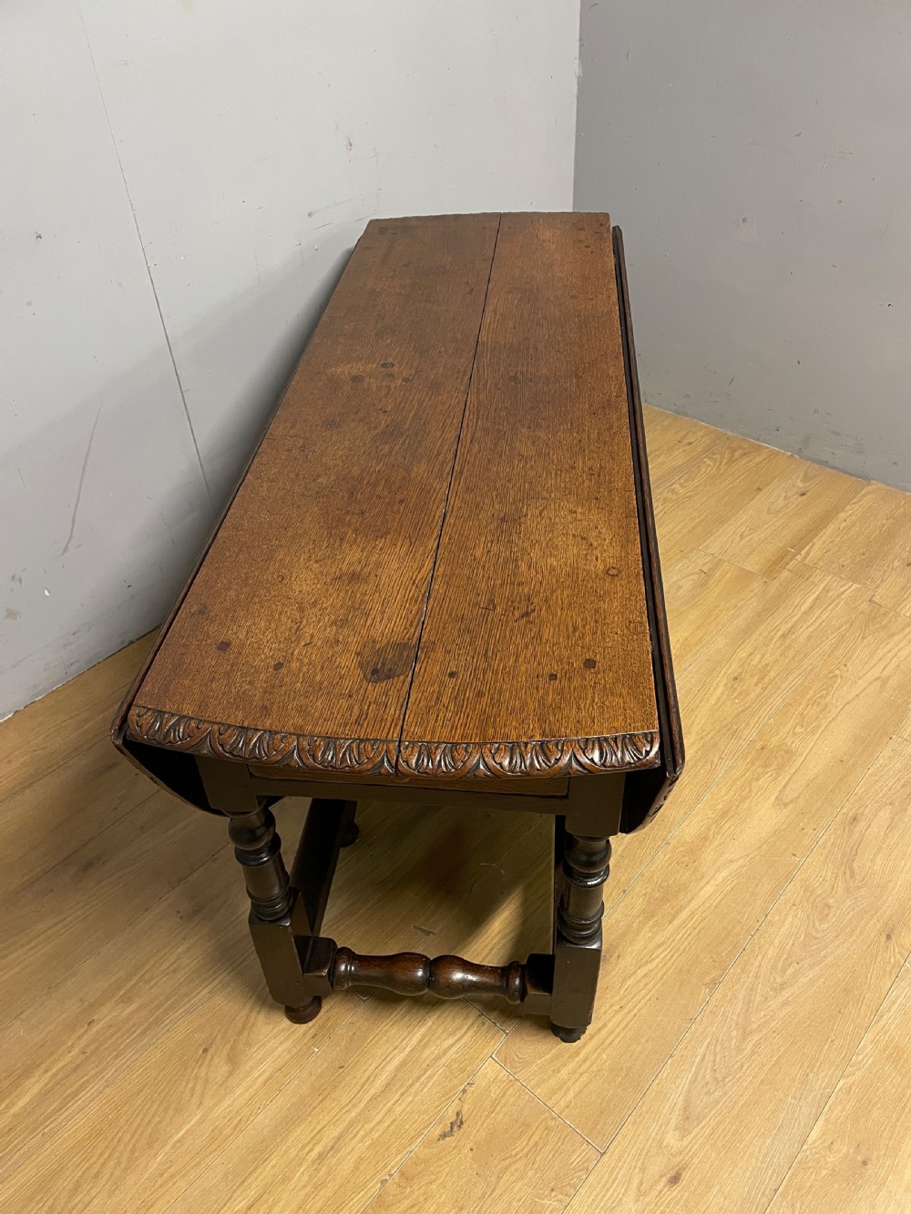 A large 19th-century dark oak drop-leaf dining table featuring turned gatelegs and a carved egg-and-dart motif along the oval table top border. View IX