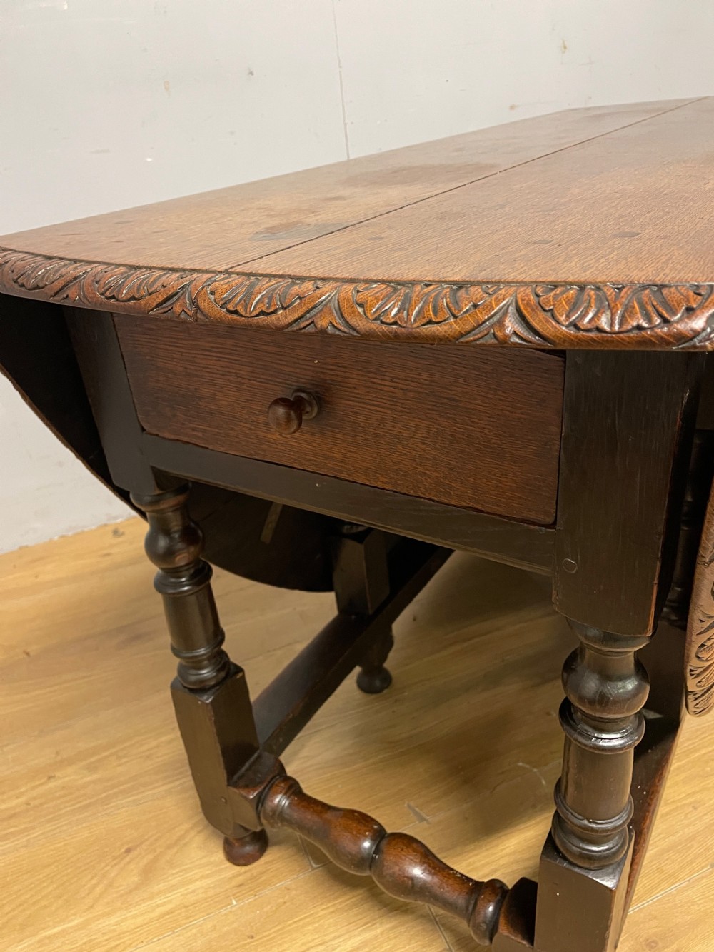 A large 19th-century dark oak drop-leaf dining table featuring turned gatelegs and a carved egg-and-dart motif along the oval table top border. View X