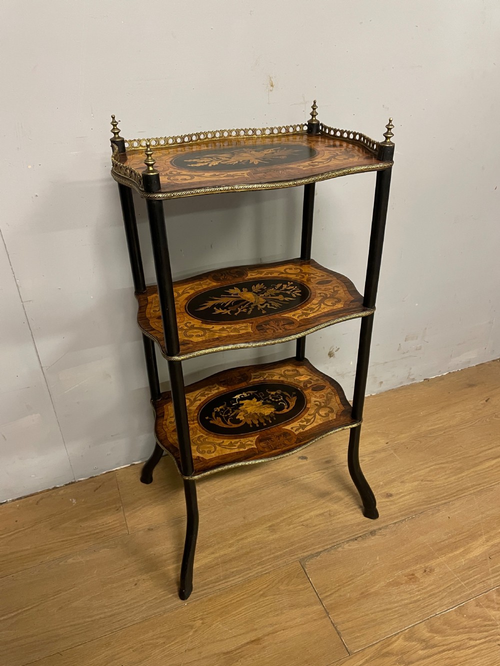 A three-tiered French etagere table featuring detailed floral marquetry wood inlays, dark turned supports, and a top shelf finished with a pierced brass gallery. View II