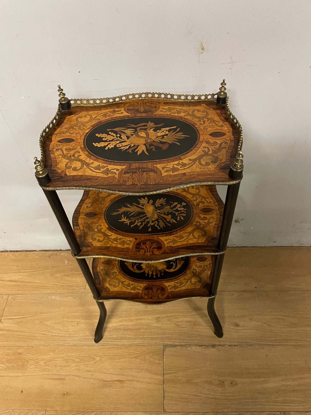 A three-tiered French etagere table featuring detailed floral marquetry wood inlays, dark turned supports, and a top shelf finished with a pierced brass gallery. View III