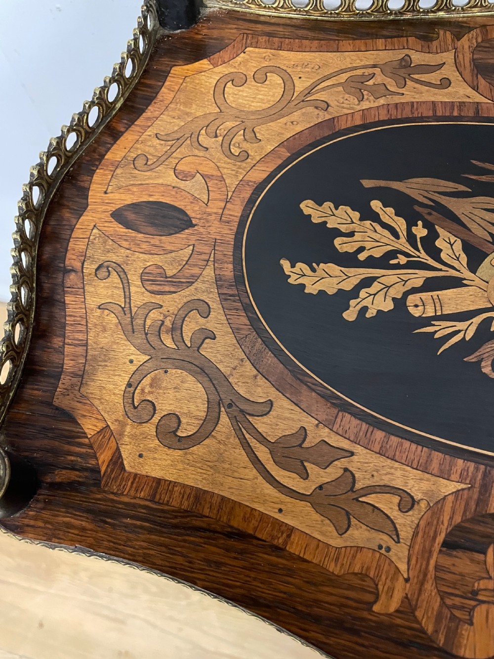 A three-tiered French etagere table featuring detailed floral marquetry wood inlays, dark turned supports, and a top shelf finished with a pierced brass gallery. View V