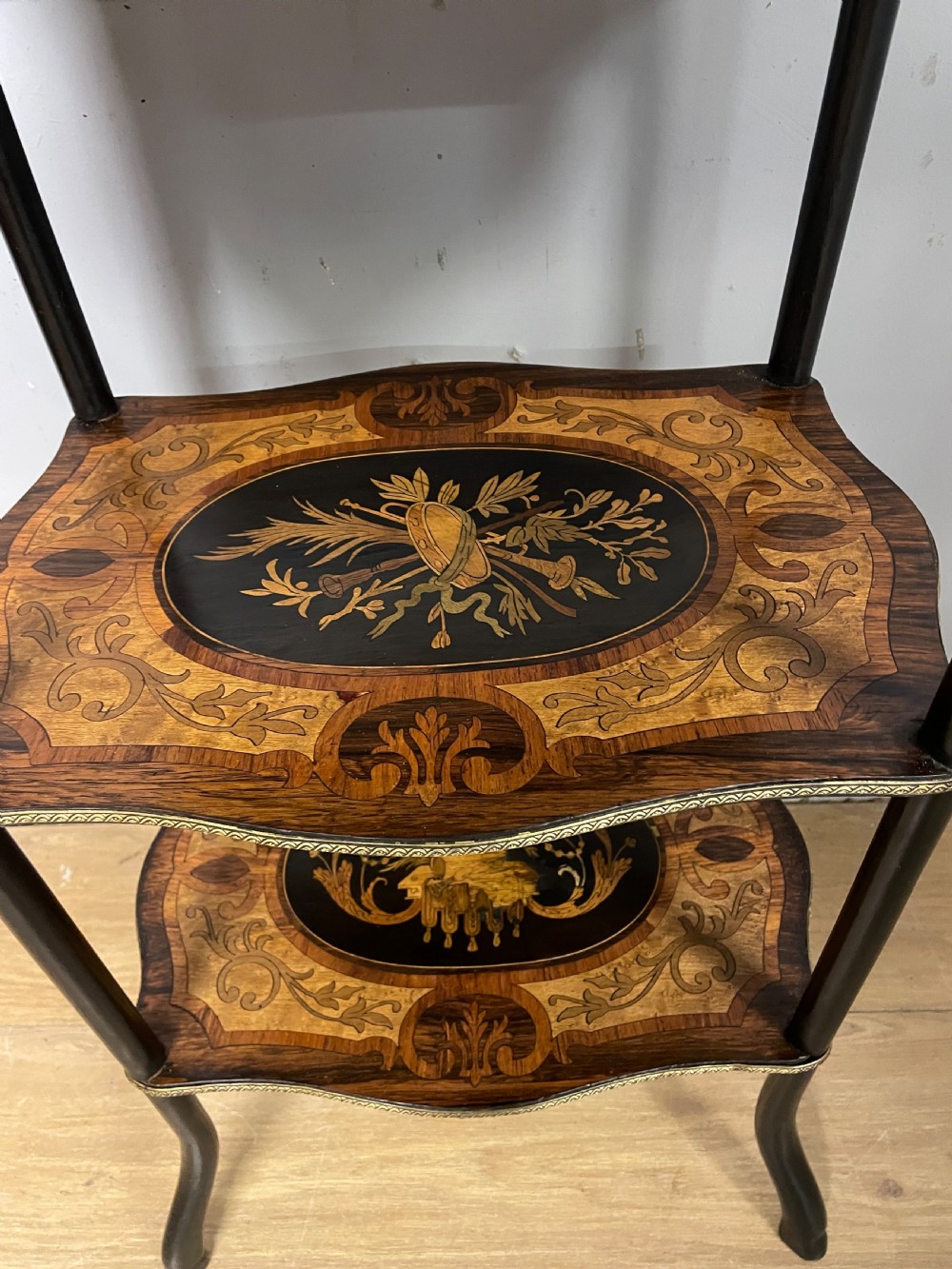 A three-tiered French etagere table featuring detailed floral marquetry wood inlays, dark turned supports, and a top shelf finished with a pierced brass gallery. View VII