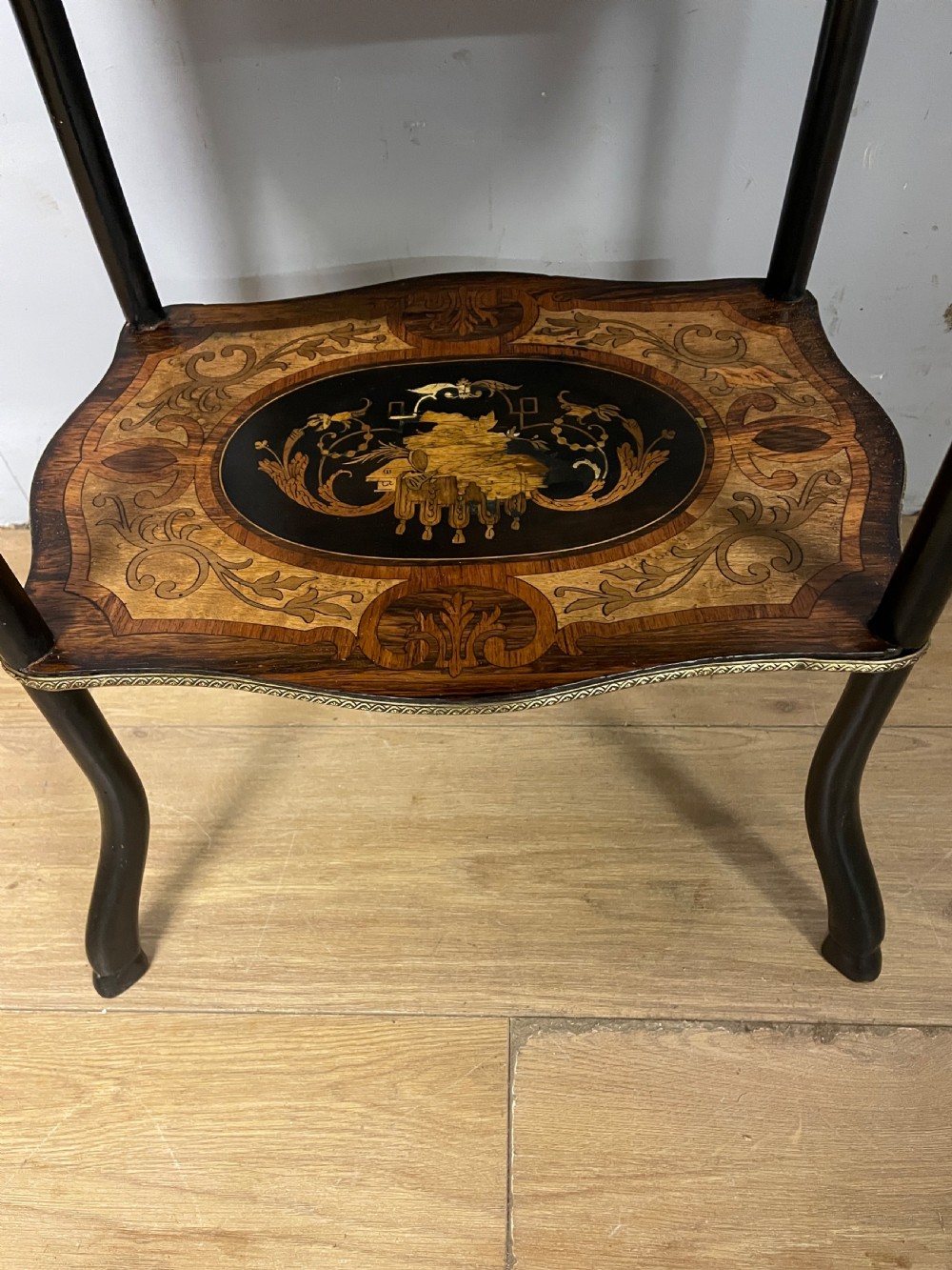 A three-tiered French etagere table featuring detailed floral marquetry wood inlays, dark turned supports, and a top shelf finished with a pierced brass gallery. View VIII