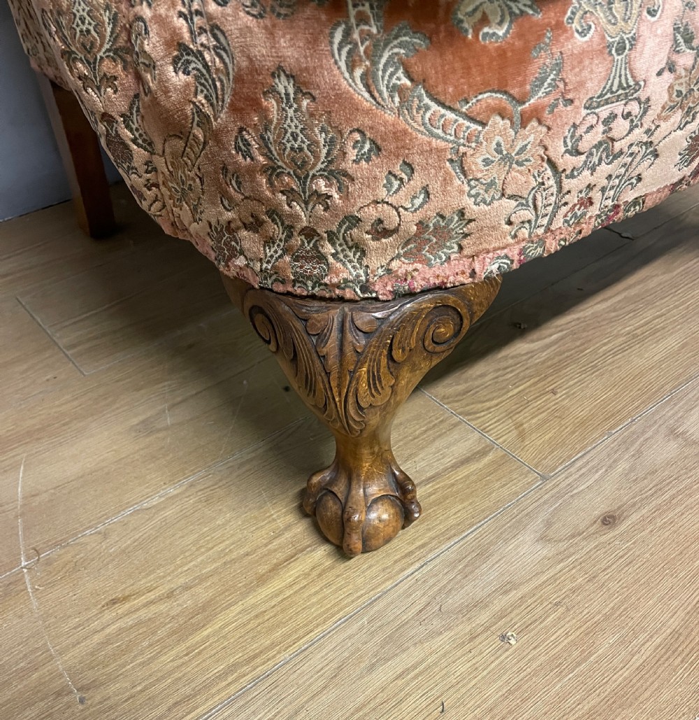 An early twentieth-century Georgian style wing armchair upholstered in patterned terracotta velvet with carved cabriole front legs ending in ball and claw feet. View IV