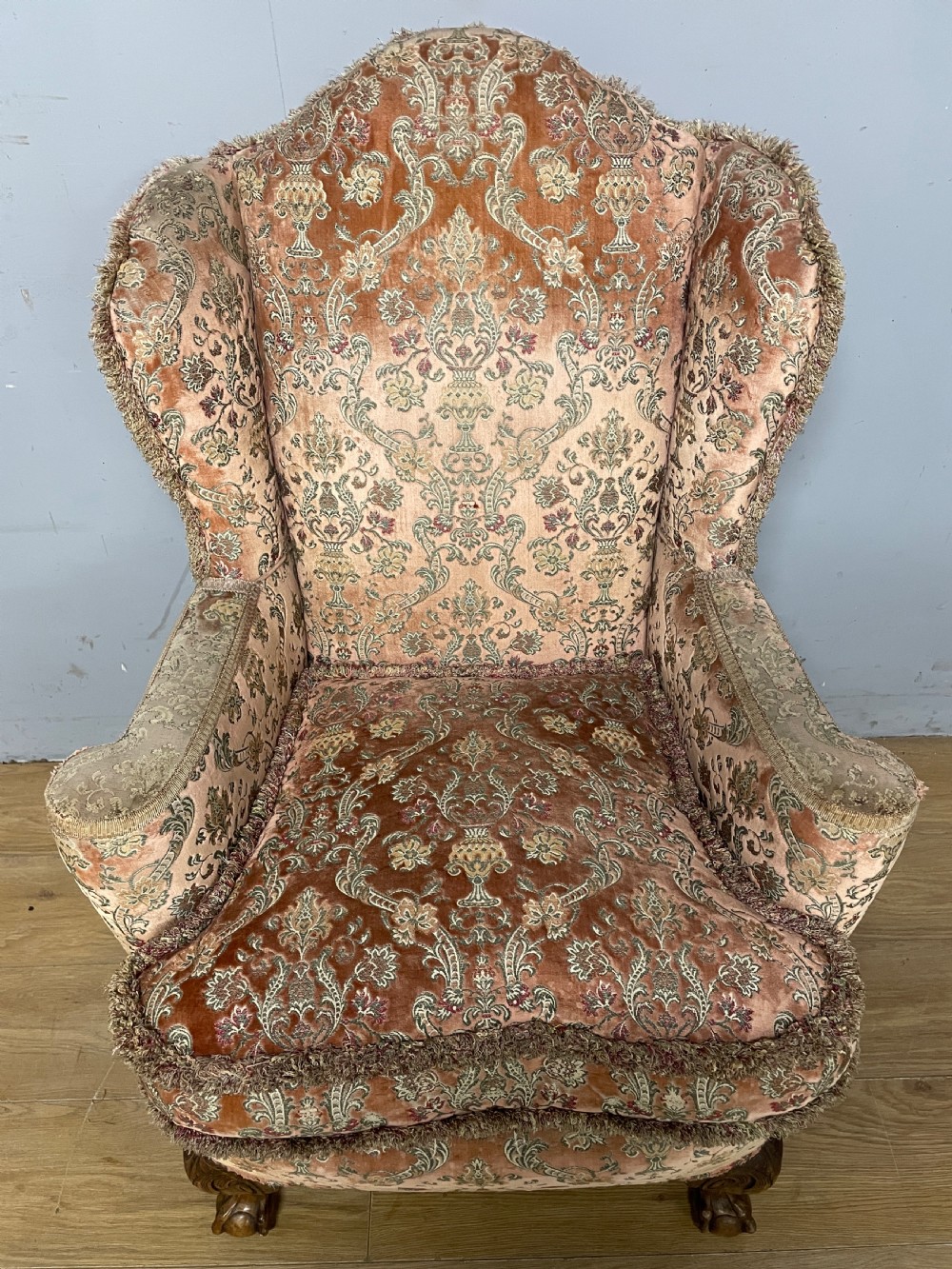 An early twentieth-century Georgian style wing armchair upholstered in patterned terracotta velvet with carved cabriole front legs ending in ball and claw feet. View V