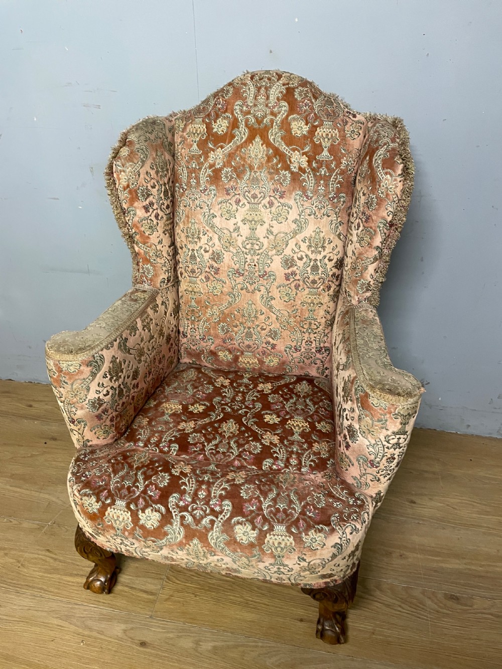 An early twentieth-century Georgian style wing armchair upholstered in patterned terracotta velvet with carved cabriole front legs ending in ball and claw feet. View VI