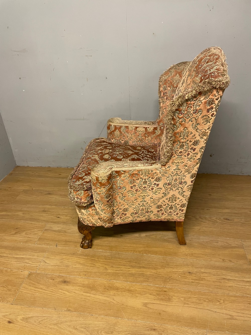 An early twentieth-century Georgian style wing armchair upholstered in patterned terracotta velvet with carved cabriole front legs ending in ball and claw feet. View VII