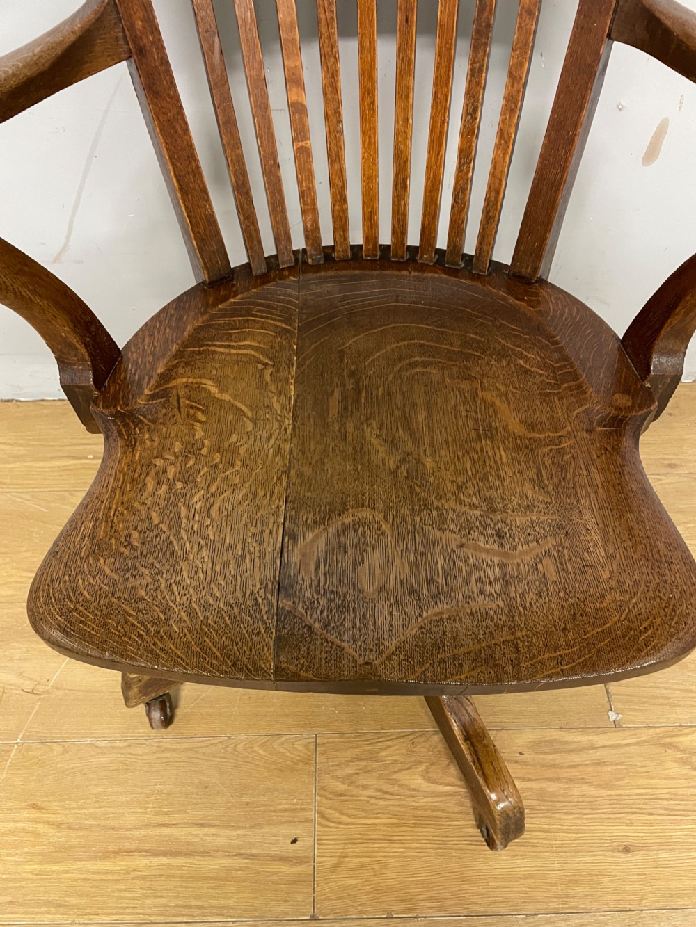 An Edwardian solid oak revolving and tilting office chair with a curved backrest, vertical spindles, and castors. View VIII