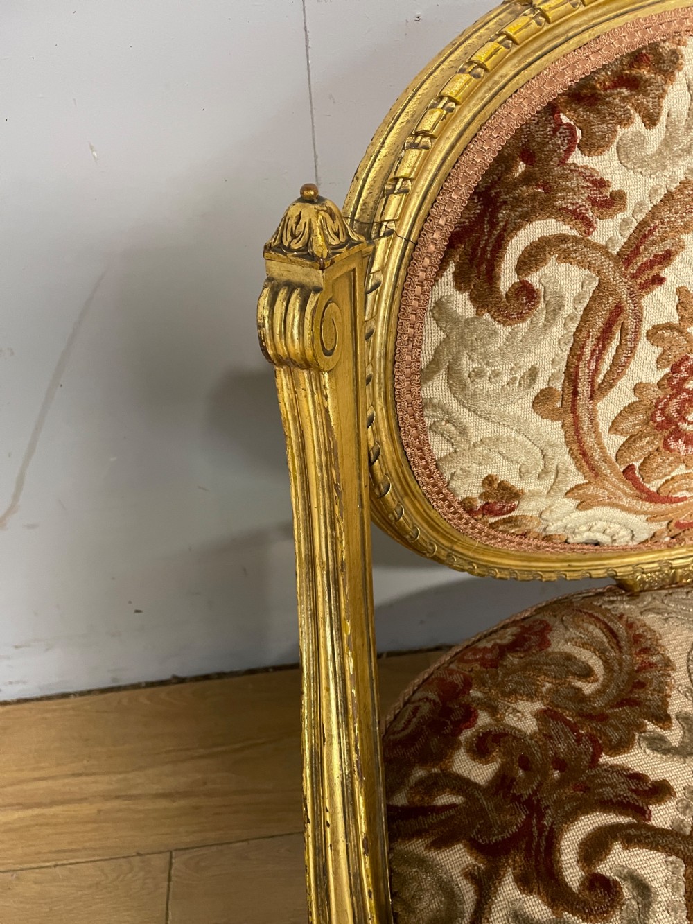 A 19th-century carved giltwood nursing chair featuring patterned burgundy velvet upholstery, an oval backrest, and short turned legs with castors. View V