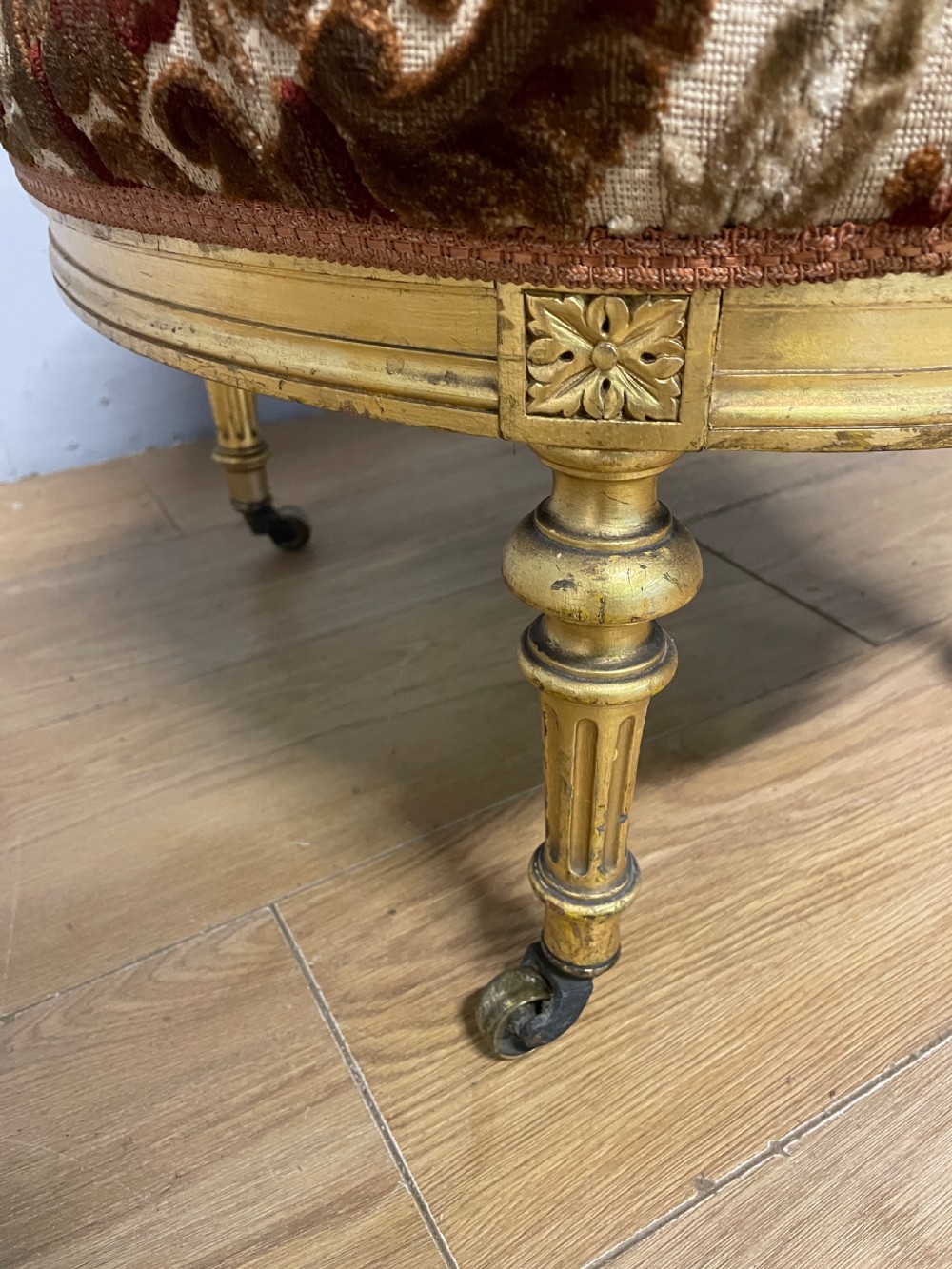 A 19th-century carved giltwood nursing chair featuring patterned burgundy velvet upholstery, an oval backrest, and short turned legs with castors. View IX