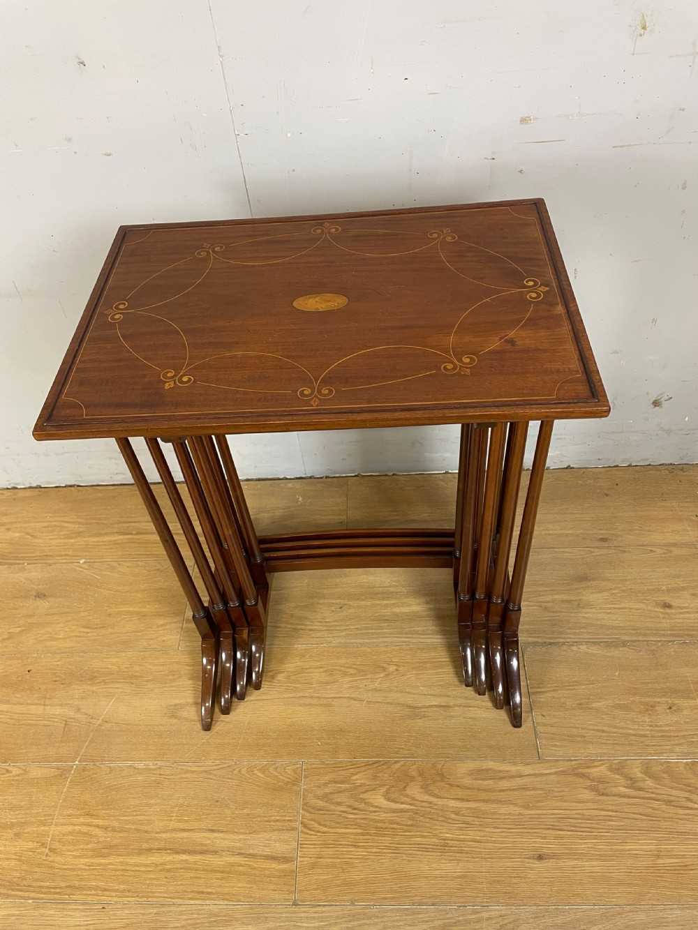An Edwardian nest of four rectangular mahogany tables featuring satinwood floral line inlay and slender turned legs resting on trestle feet. View II