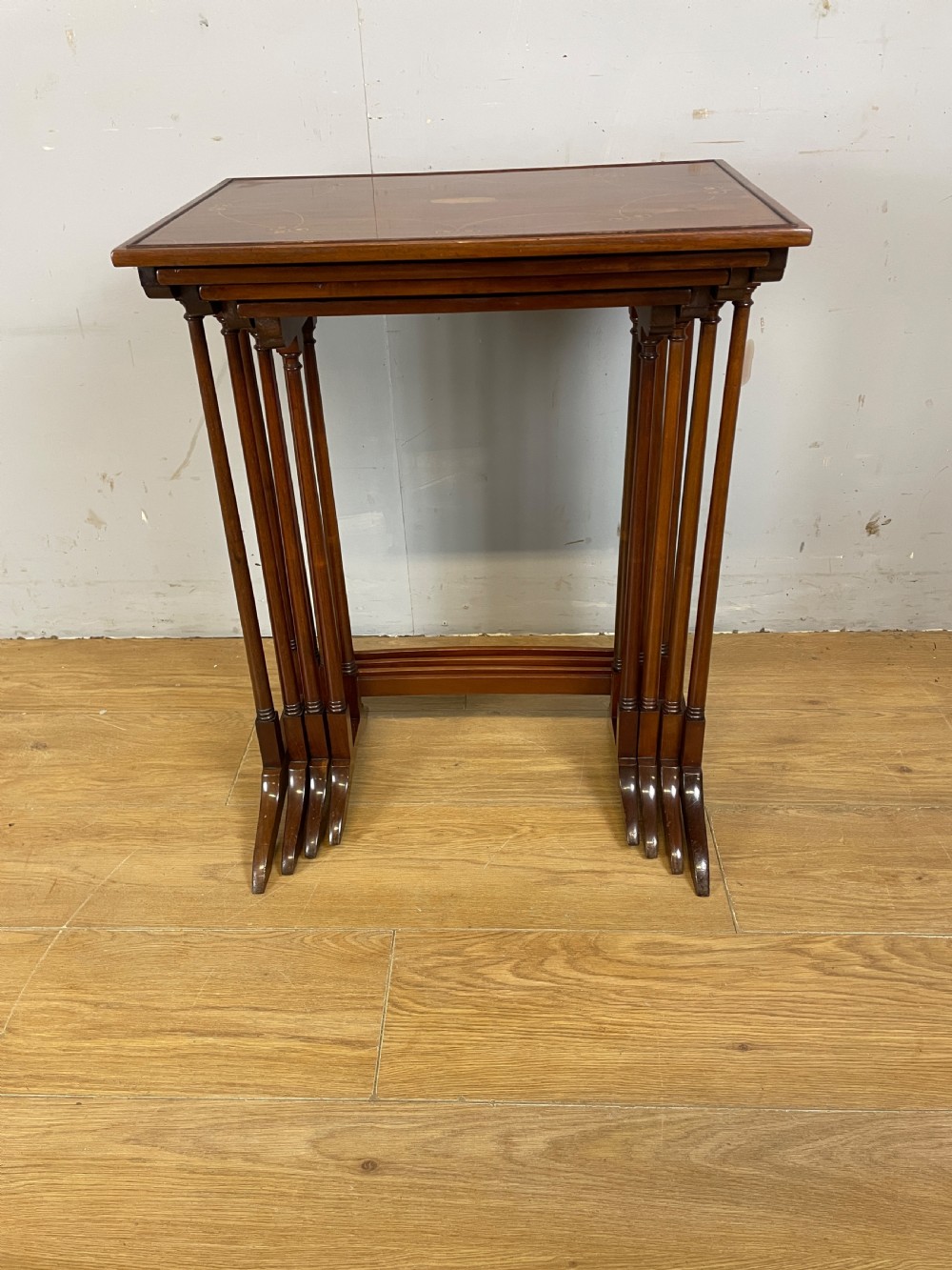 An Edwardian nest of four rectangular mahogany tables featuring satinwood floral line inlay and slender turned legs resting on trestle feet. View III