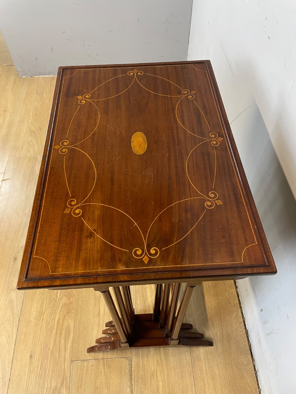 An Edwardian nest of four rectangular mahogany tables featuring satinwood floral line inlay and slender turned legs resting on trestle feet. View IV