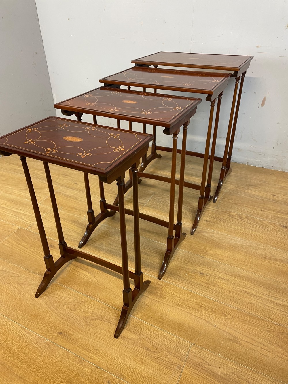 An Edwardian nest of four rectangular mahogany tables featuring satinwood floral line inlay and slender turned legs resting on trestle feet. View VII