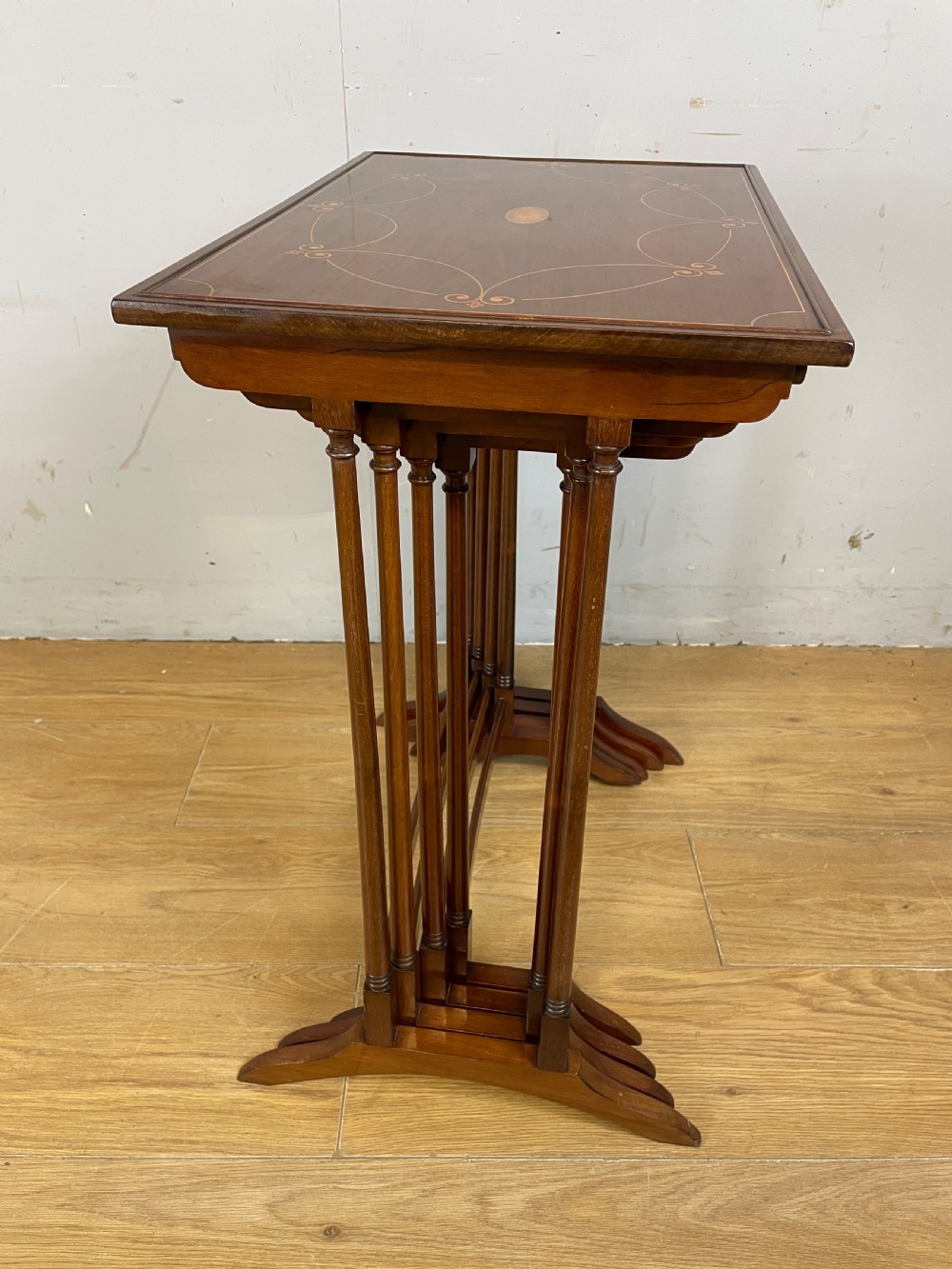 An Edwardian nest of four rectangular mahogany tables featuring satinwood floral line inlay and slender turned legs resting on trestle feet. View IX
