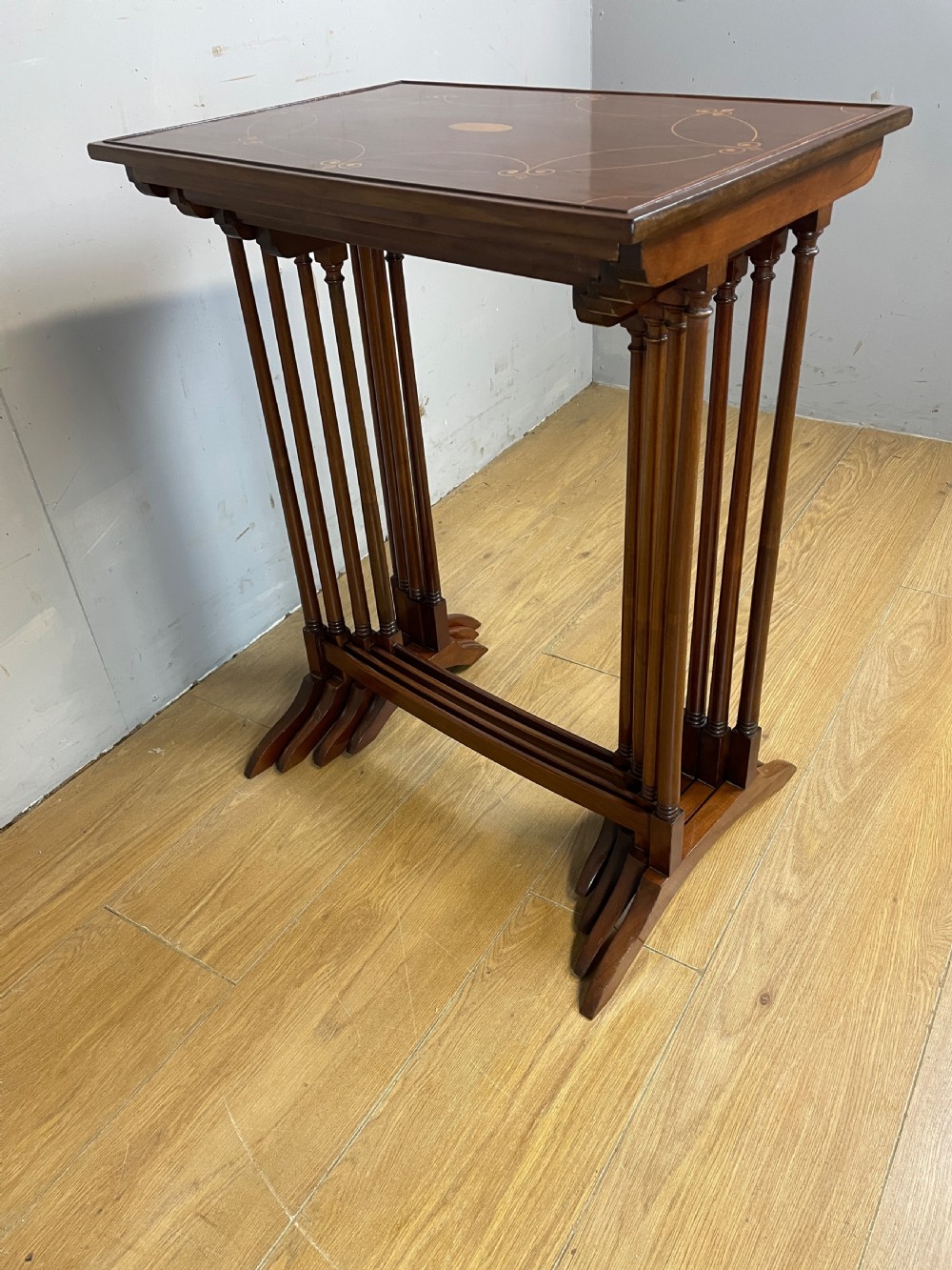An Edwardian nest of four rectangular mahogany tables featuring satinwood floral line inlay and slender turned legs resting on trestle feet. View X